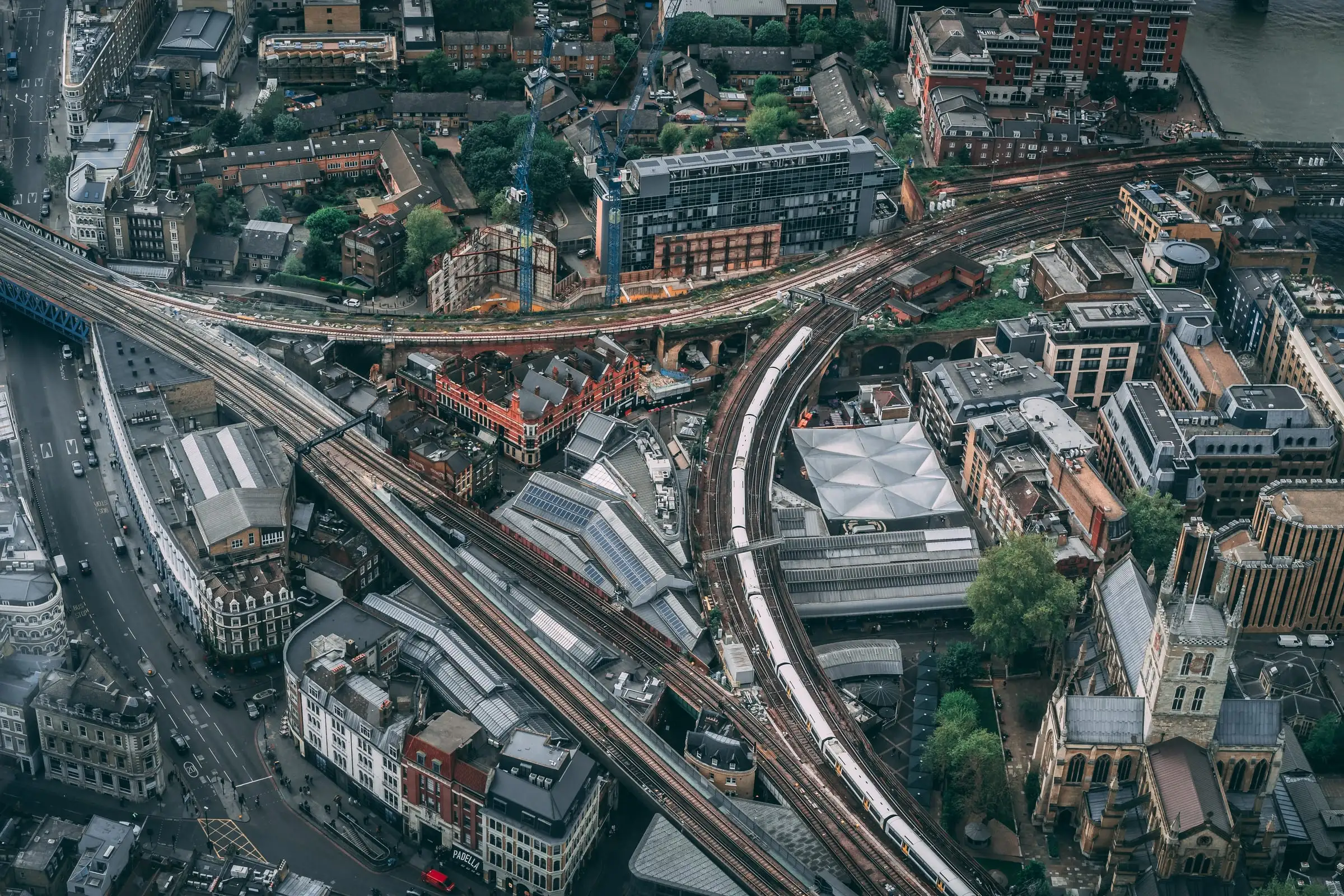 Railway viaducts curving between city buildings seen from above, with a train on the tracks.